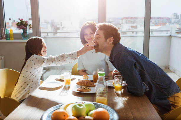 istock daughter feeding her dad at breakfast 667578428