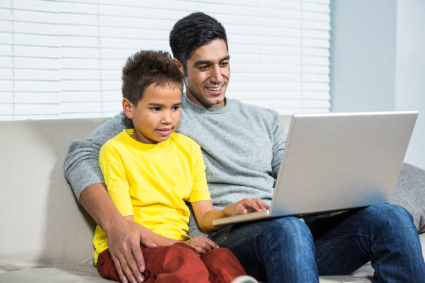 istock Smiling father and son using laptop on the sofa 667580828