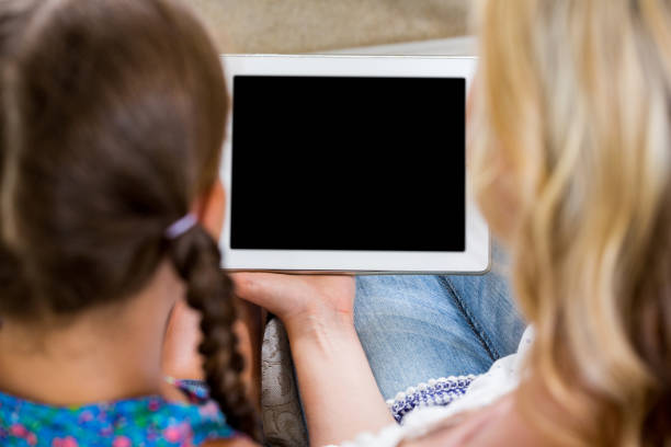 母と娘はデジタル タブレットの背面図 - digital tablet looking child offspring ストックフォトと画像