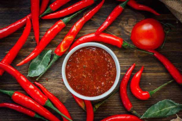 istock Red hot chili peppers and salsa or adjika in white ceramic bowl. 667599740