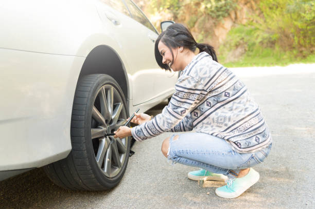 jóvenes, cambiar una rueda pinchada - car stranded women breakdown fotografías e imágenes de stock