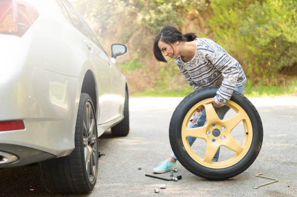 jóvenes, cambiar una rueda pinchada - car stranded women breakdown fotografías e imágenes de stock