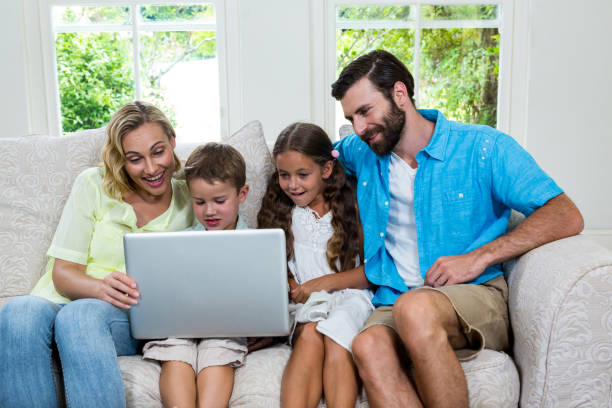 istock Smiling children with parents using laptop at home 667624802