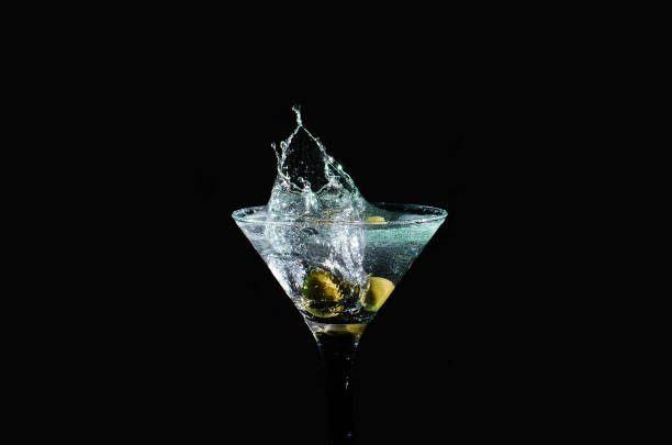Olive splashing on cocktail isolated on black background