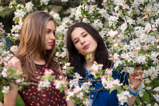 Two Young Women Enjoying The Scent Of Blossoming Tree – Free Stock Photo