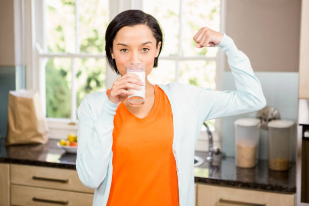 istock Happy brunette drinking milk and showing bicep 667629280