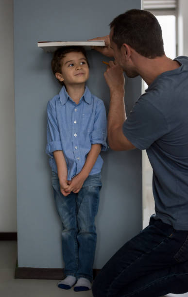 istock Happy father measuring his son at home 667633098