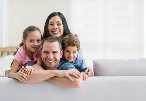 Portrait of a happy Latin American family at home on the sofa and looking at the camera smiling - lifestyle concepts