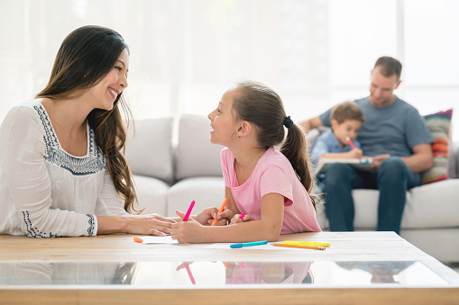 Portrait of a happy Latin American family at home with kids doing their homework and parents supervising - lifestyle concepts