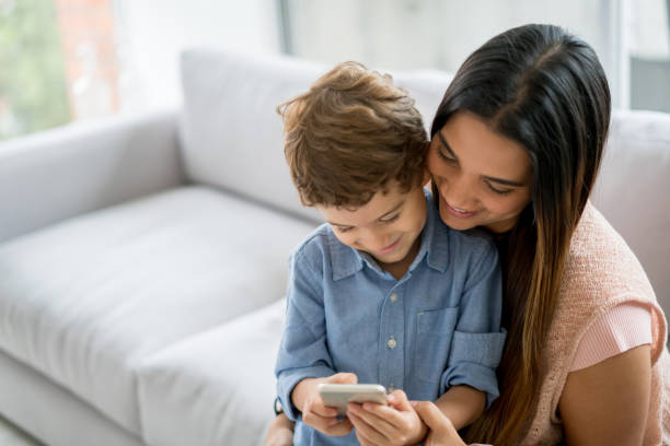 istock Mother and son at home social networking on a cell phone 667633338