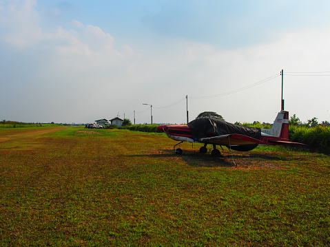 An old turprop one engine plane is parking at the field near the runway. Ready for the trainee to be learnt.