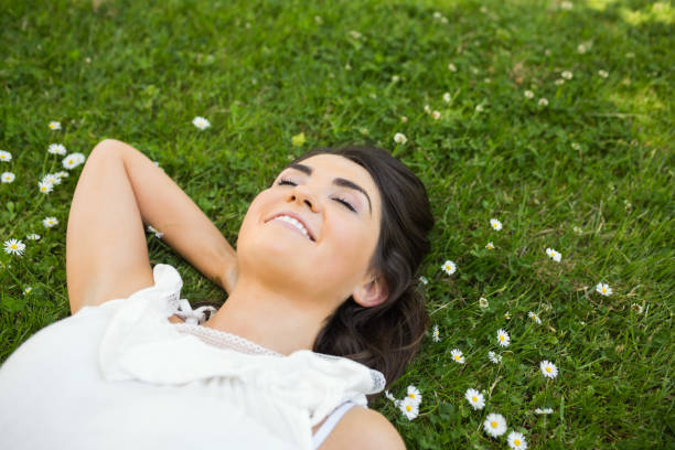 istock Happy woman relaxing with hand behind head on grassland 667647690