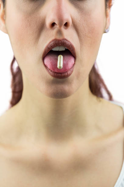 istock Woman with pill in mouth 667648950