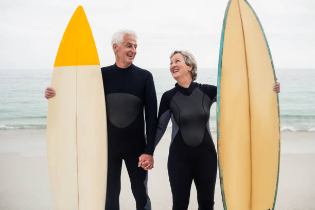 istock Senior couple with surfboard holding hand on the beach 667650024