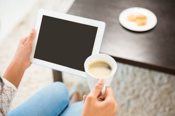 istock Smiling casual woman using her tablet while holding coffee 667650288