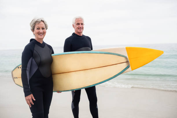 istock Senior couple with surfboard standing on the beach 667652464