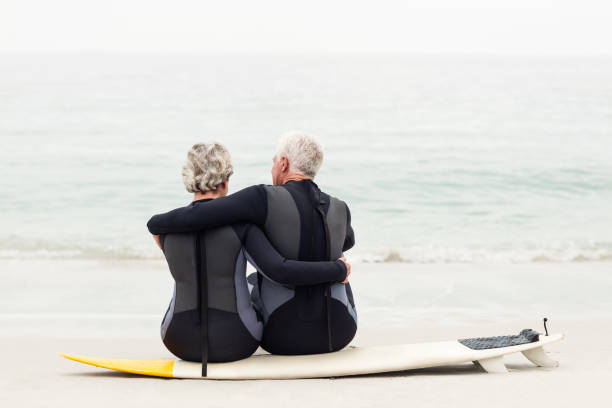 istock Rear view of couple sitting on surfboard 667652676