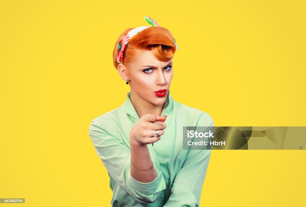 It's you! Portrait angry annoyed pin up retro style woman getting mad pointing finger at you camera showing hand gesture this is you, you chosen, isolated on yellow wall background.  Negative emotions Women Stock Photo