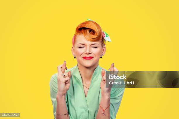 Closeup Hopeful Beautiful Young Woman Pin Up Style Retro Crossing Her Fingers Eyes Closed Hoping Asking Best Isolated Yellow Background Human Face Expression Emotions Feeling Attitude Reaction Stock Photo - Download Image Now