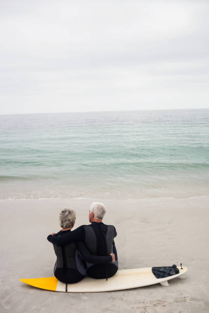 istock Rear view of couple sitting on surfboard 667652824