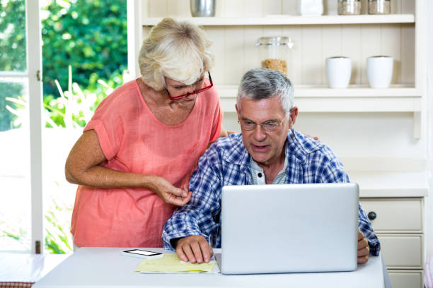istock Wife discussing with senior man on laptop at table 667657034
