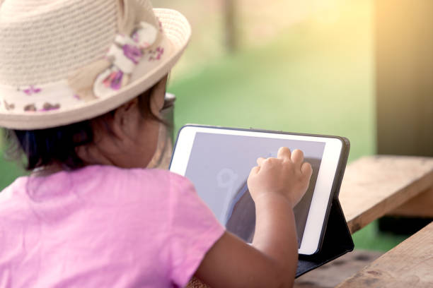istock Asian little girl is playing tablet 667661194