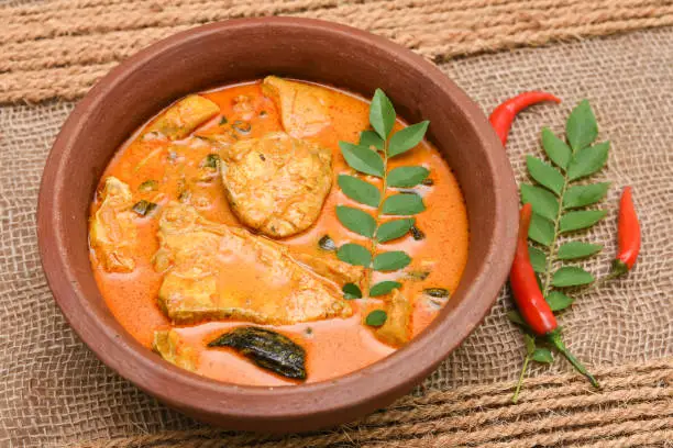 Top view of spicy and hot king fish curry with green curry leaf Kerala India. Barracuda Fish curry with green chili, coconut milk and mango Asian cuisine..