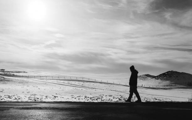 istock a man walking away on an empty desolated road 667678612