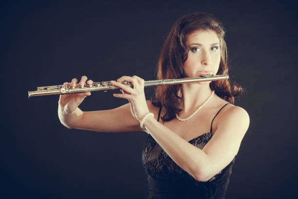 istock Woman playing transverse flute on black. 667685532