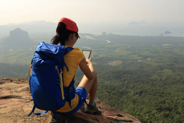 istock successful woman hiker reading electronic book hiking on mountain peak 667689098