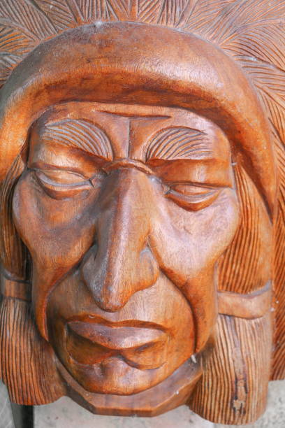 деревянная голова индийской на фоне стены - native american statue wood carving стоковые фото и изображения