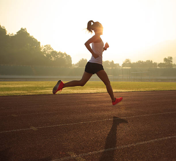 istock Young woman running during sunny morning on stadium track 667698638