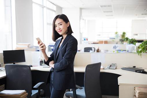young woman wearing a black suit,using the phone in the office
