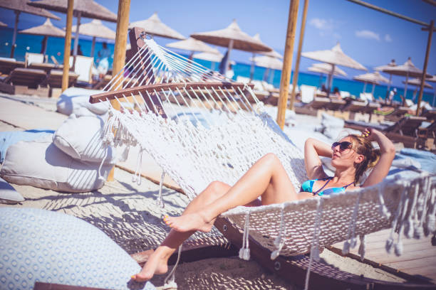 istock Happy young woman lying in hammock on tropical beach 667707242
