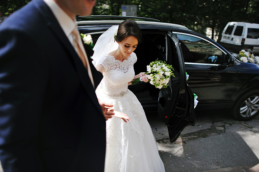 groom take hand his bride out from wedding car