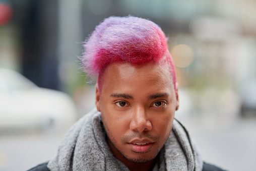 Portrait of a young man with a funky hairstyle posing outdoors