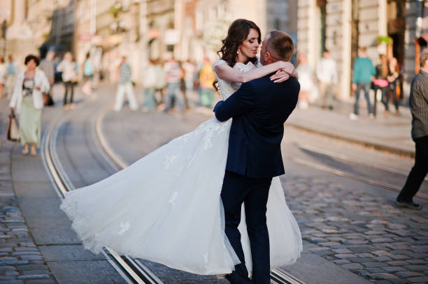 istock Groom holding on hands his bride on background old city 667715316