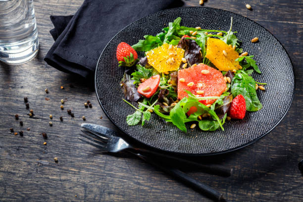 istock Grapefruit and orange mix salad with pine nuts on black plate and dark background 667722530