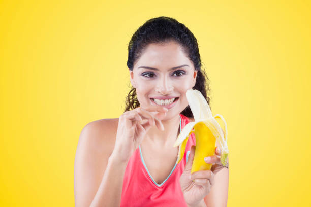 istock Woman peeling a banana on yellow background 667727478