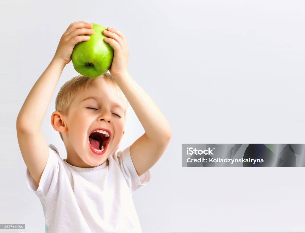 small boy holds a big green apple, small boy holds a big green apple, healthy food and vitamins, smiling, white background, soft focus Child Stock Photo