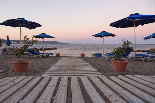Faliraki beach with sunbeds and umbrellas at sunset, Rhodes