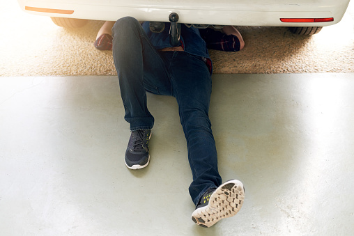 High angle shot of an unrecognizable man working under his car