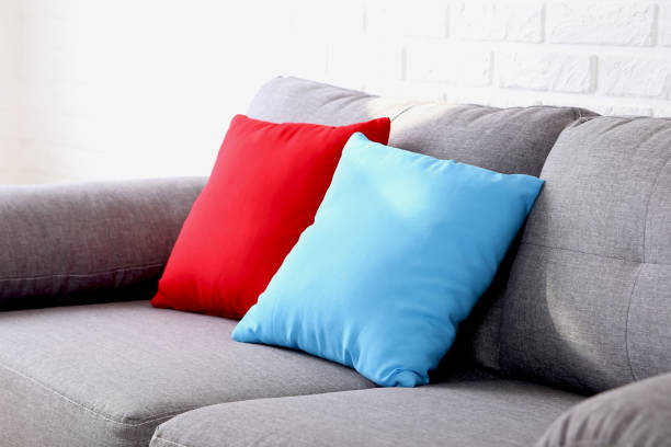 Colorful pillows on grey sofa on a brick wall background