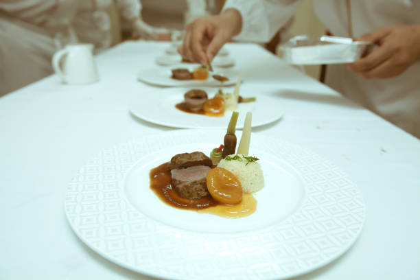 istock chef using chopsticks tong sliced beef put on the white plate in luxury dinner party, Blurry background with vintage color style. 667754710