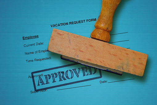 Formulario de solicitud de vacaciones y sello madera sobre fondo azul photo