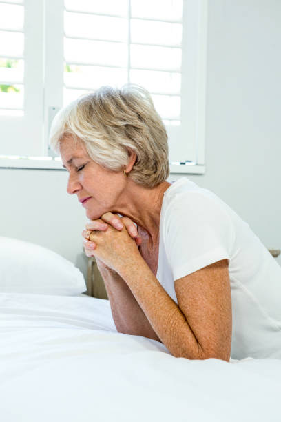 istock Aged woman praying at home 667764350