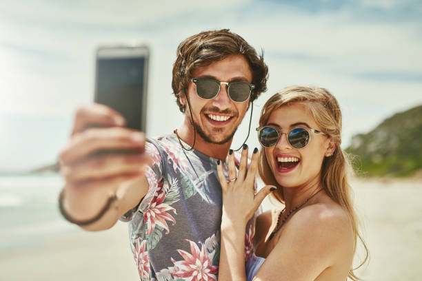 We're tying the knot! Shot of an affectionate young couple taking selfies after their engagement on the beach jewelry photos stock pictures, royalty-free photos & images