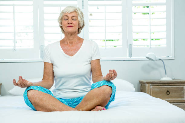 istock Senior woman doing yoga on bed 667766702