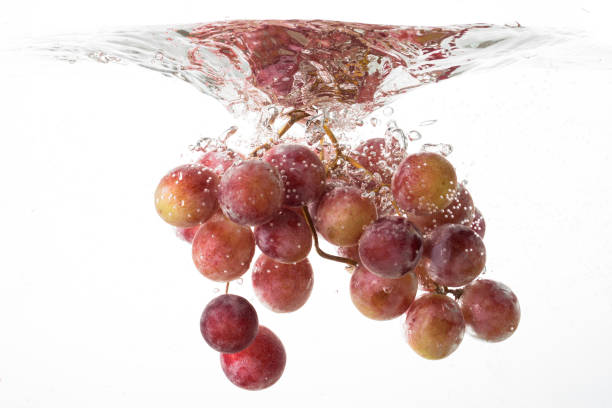 istock Grapes falling into water close up on white background 667770756