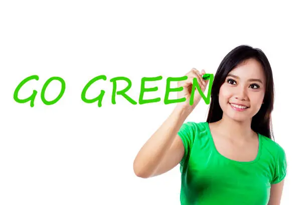 Photo of a young pretty woman writing a text of Go Green on the transparent screen, isolated on white background. Concept of Earth Day